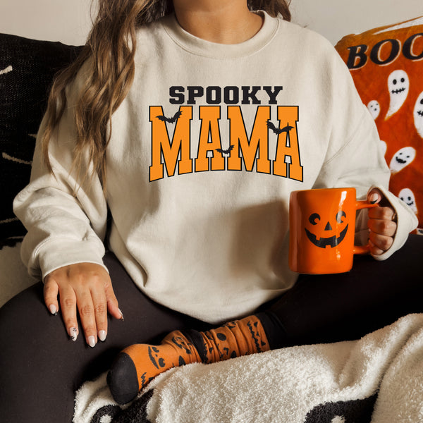 sweatshirt with halloween decorations and jackolanter mug with screen print that says spooky mama for halloween season